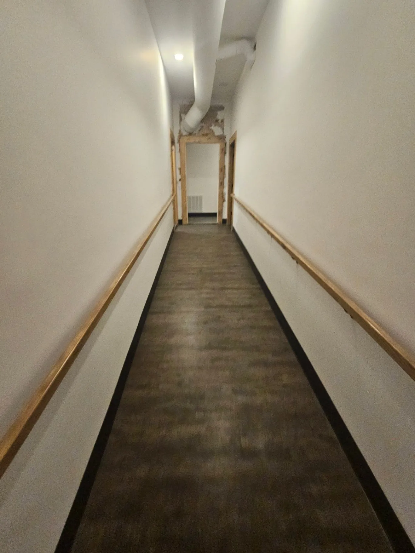 Completed hallway with wood handrails leading toward a treatment room