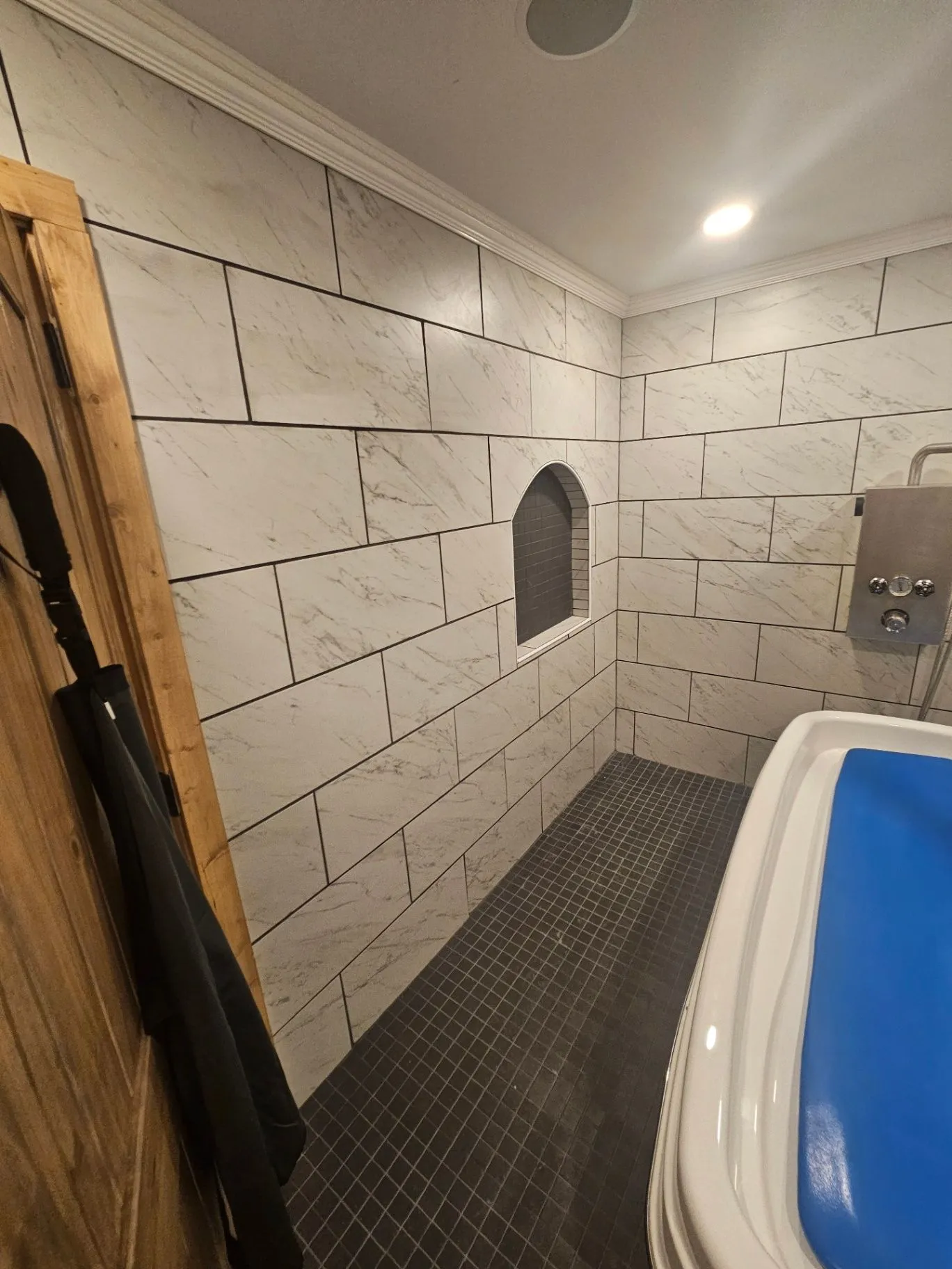 Completed tiled spa wet room with a recessed niche and blue soaking tub