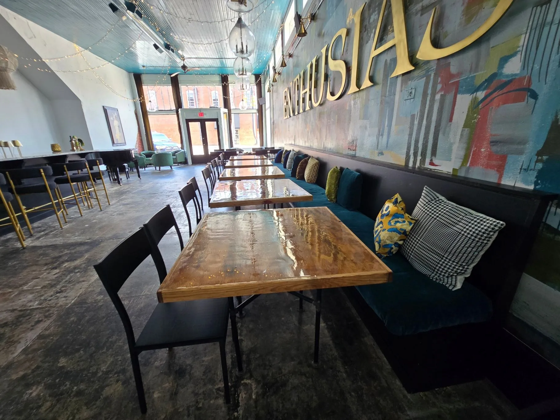 Completed Wine Bar dining room with a mural wall, blue banquette, and wood tables